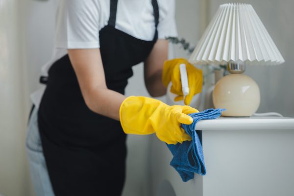 Housekeeper cleaning the furniture in the house, Wear an apron and rubber gloves to protect against cleaning chemicals, female wiping down tables with cleaning spray, cleaning idea.